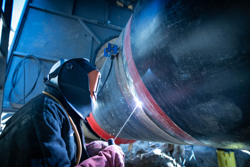 Man welding for pipe replacement, ship repairs